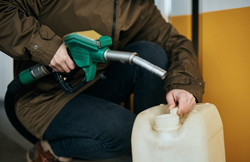 Close-up of woman pouring gasoline in a barrel at gas station.